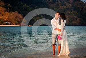 bride and groom walk at beach at dawn