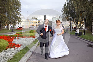 Bride and groom walk in city park