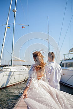 The bride and groom walk near the yacht club