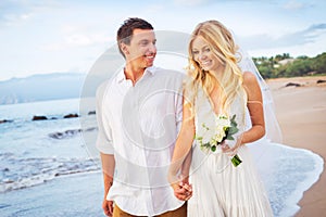 Bride and Groom Walking on Beautiful Tropical Beach at Sunset, R photo