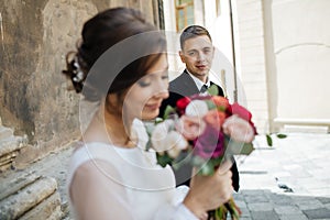 Bride and groom walking in a sunny city at large buildings