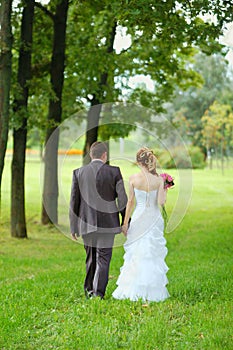 Bride and groom walking in the park