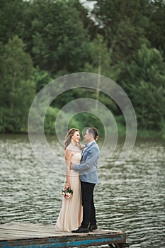 Bride and groom walking on the river, smiling, kissing