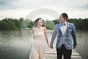 Bride and groom walking on the river, smiling, kissing