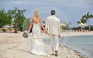 Bride and groom walking together on beach