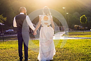 Bride and groom walking towards sunset holding hands