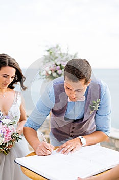 the bride and the groom at the wedding ceremony, the groom signs