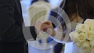 Bride and groom at wedding ceremony. Man put on a ring on a woman finger.