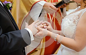 the bride and groom during the wedding ceremony put wedding rings on their fingers