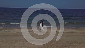 The bride and groom in wedding clothes are walking along the seashore, hugging, kissing, running, enjoying