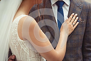 Bride and groom wedding couple with closeup on woman`s hand on man`s chest. brown checkered jacket