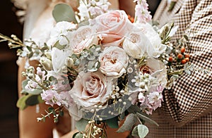 Bride and groom on wedding day hug and show love with a wedding bouquet of rose flowers