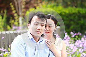 Bride and groom in wedding dress with elegant hairstyle, with white wedding dress Sitting on the bench next to the fence