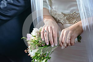 Bride and groom at the wedding with focus on bride`s manicured hands with engagement ring and gold wedding band