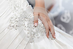 Bride hand againts a wedding dress