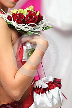 Bride hand holds bouquet of roses and reticule photo