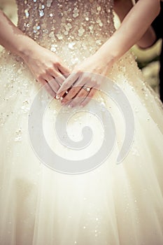 Bride hand with a wedding ring on the background of dress