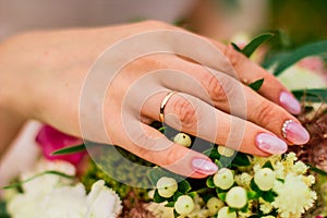 Bride hand with wedding ring on a colorful wedding bouquet close up