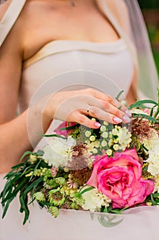 Bride hand with wedding ring on a colorful wedding bouquet close up