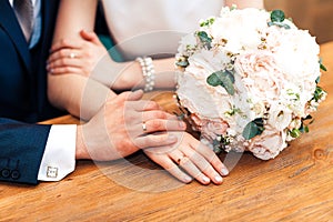 Bride hands with ring and wedding bouquet of flowers