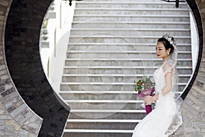 Bride hold bridal bouquet with white wedding dress near a brick arch