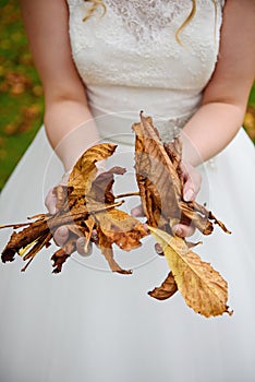 Bride holding autumn leafs.