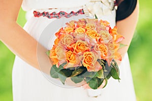 A bride holding a beautiful bouquet of orange roses