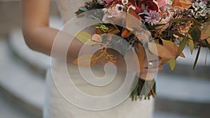 Bride is holding beautiful wedding bouquet of different flowers. Bridal bouquet on wedding day. Bouquet of beautiful