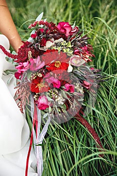 bride holding a bouquet of red flowers of zinnias