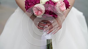 Bride holding bouquet of white, pink and red roses. Waving ribbons. Outdoors slowmotion