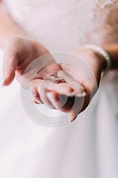 Bride holding engagement ring on her hands