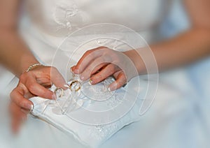 Bride holding lace pad with two gold wedding rings