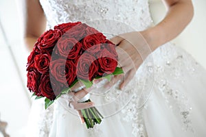 Bride holding a posy of deep red roses
