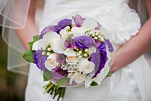 Bride holding purple and white wedding bouquet