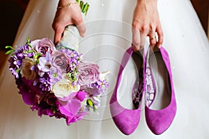 Bride holding shoes and colorful bouquet