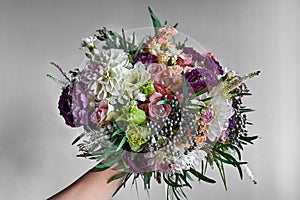 Bride holding a Wedding Bouquet in a Hand with colorful red, pink and White Petals
