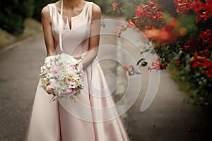 Bride holding wedding bouquet of pink roses and white flowers in