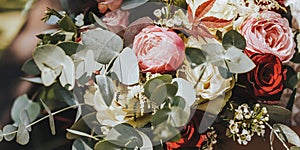 Bride holding wedding bouquet with red and pink flowers