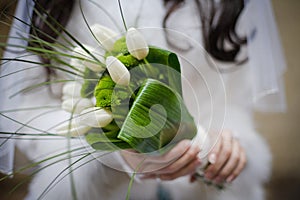 Bride holding wedding bouquet from white tulipes and golden-daisies