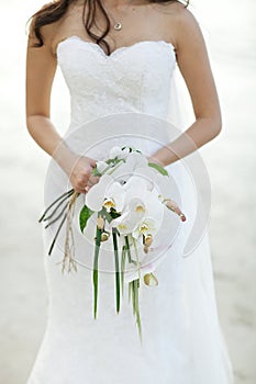Bride holding white orchid flower wedding bouquet