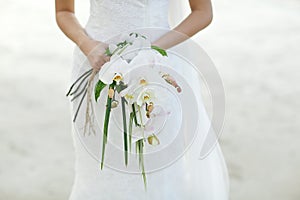 Bride holding white orchid flower wedding bouquet