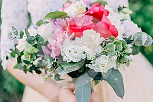 The bride holds a beautiful wedding bouquet of pink and white flowers in her hands