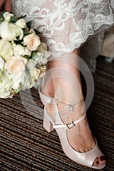 The bride holds a bouquet near her feet in shoes