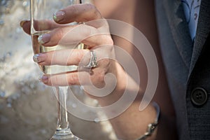 The bride holds a champagne flute and has a ring on her finger