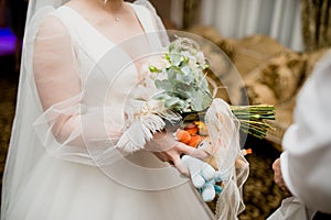 The bride holds her beautiful wedding bouquet with gentle hands