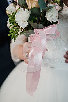 The bride holds her beautiful wedding bouquet with gentle hands