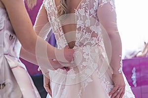 The bride holds her hand on a white beautiful bridal dress and shows her engagement ring.