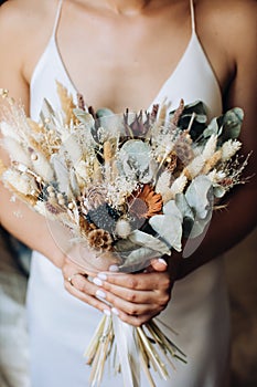 The bride holds in her hands an elegant bouquet of wildflowers in the style of boho. Wedding trends