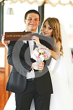 Bride holds a lettering 'Reserved' in a front of a groom