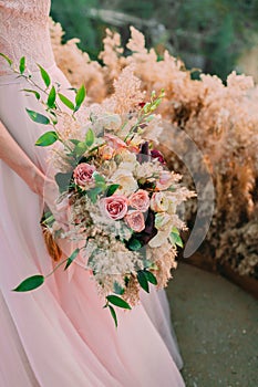 A bride holds rustic wedding bouquet consisting of different flowers. Decoration Artwork